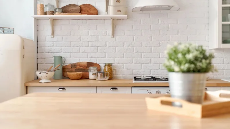 bright kitchen with white brick wall, wooden boards and a plant on a wooden table
