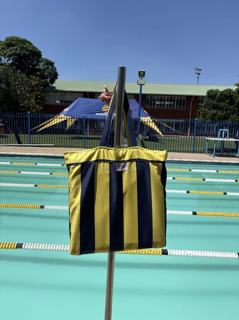 Yellow and navy striped matching bag beside a swimming pool