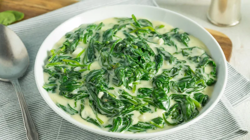 creamed spinach in a white bowl on a striped linen cloth